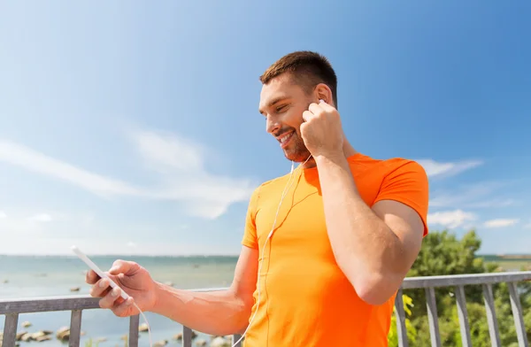 Lächelnder junger Mann mit Smartphone und Kopfhörer — Stockfoto