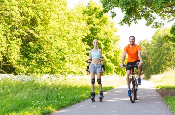 Coppia felice con pattini e bicicletta — Foto Stock