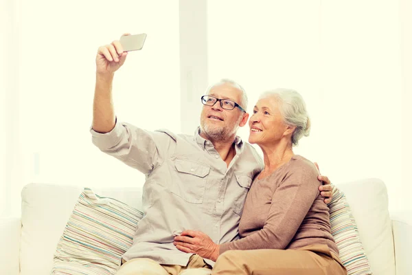 Casal sênior feliz com smartphone em casa — Fotografia de Stock