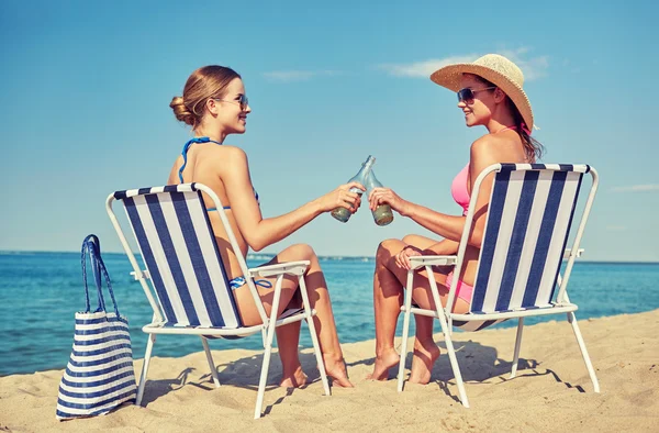 Happy women clinking bottles and drinking on beach — Stock Photo, Image