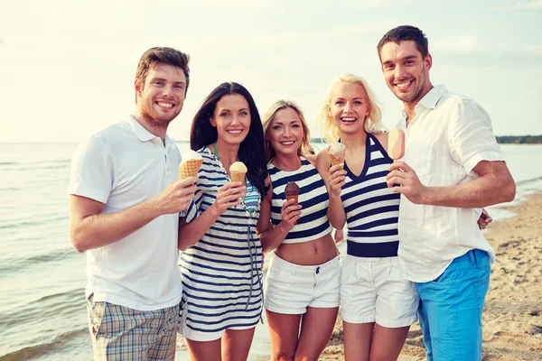 Amigos sonrientes comiendo helado en la playa —  Fotos de Stock