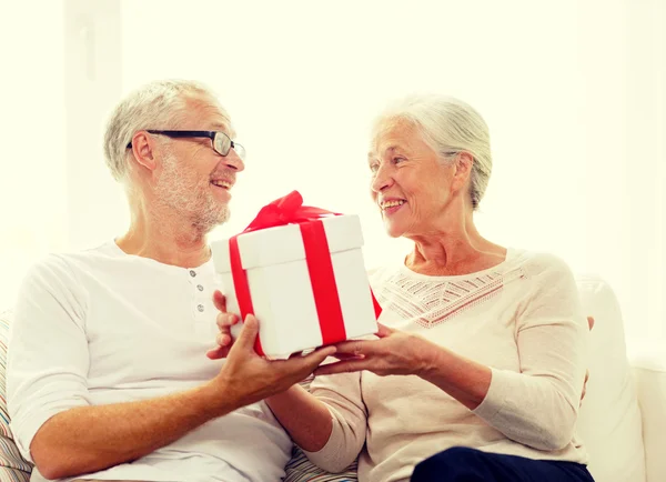 Feliz pareja de ancianos con caja de regalo en casa —  Fotos de Stock