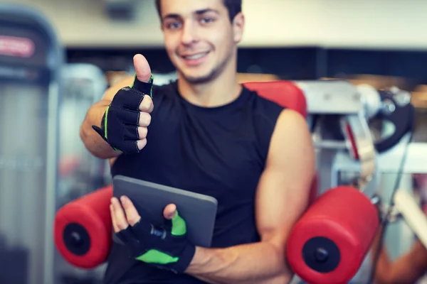 Young man with tablet pc showing thumbs up in gym — Stock Photo, Image