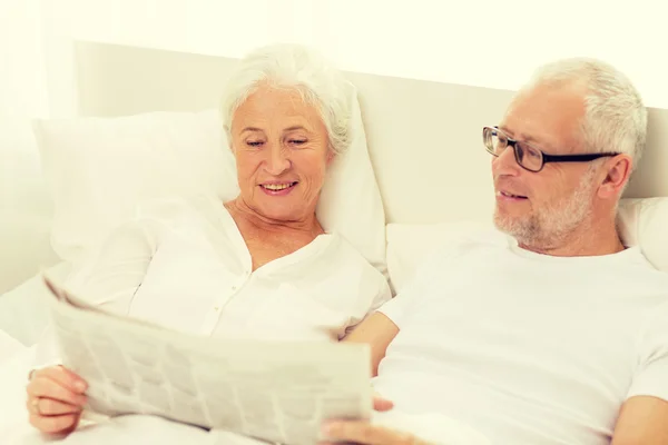 Glückliches Seniorenpaar mit Zeitung im Bett — Stockfoto