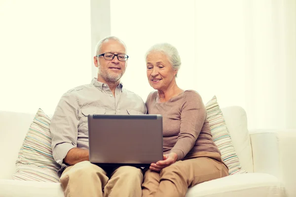 Feliz pareja de ancianos con portátil en casa —  Fotos de Stock