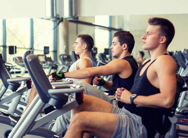 Uomini che si allenano in cyclette in palestra — Foto Stock