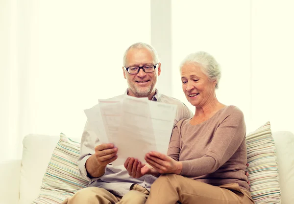 Happy senior couple with papers at home — Stock Photo, Image