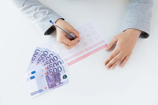 Primer plano de las manos con billete de lotería y dinero — Foto de Stock