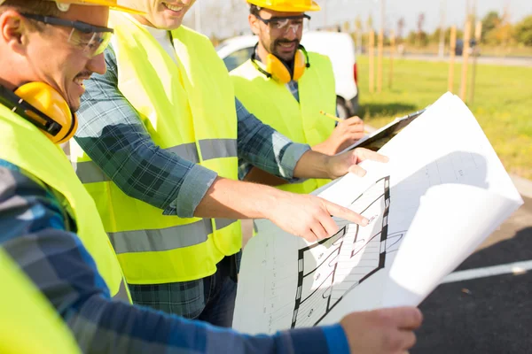 Close up of builders with blueprint at building — Stock Photo, Image