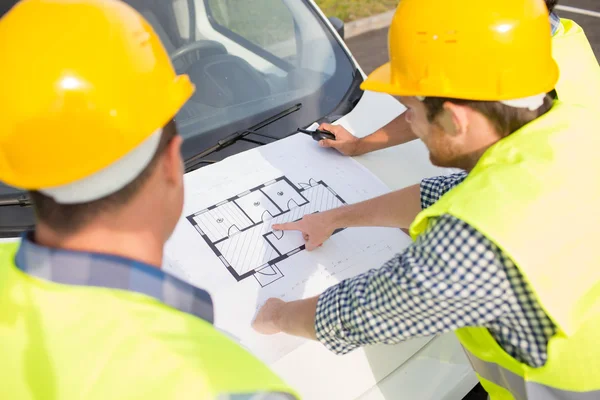 Nahaufnahme von Bauarbeitern mit Blaupause auf der Motorhaube — Stockfoto