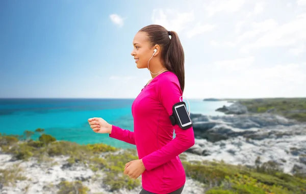 Happy woman with smartphone running on beach — 图库照片