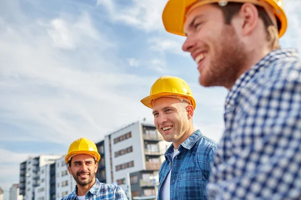 Grupp av leende byggare i hardhats utomhus — Stockfoto