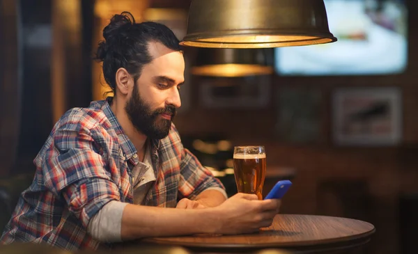 Muž s smartphone a pivo textilie na baru — Stock fotografie