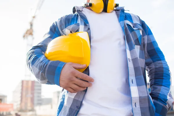 Närbild av builder holding hardhat på byggnad — Stockfoto