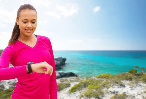 Smiling woman with heart rate watch on beach — Stock fotografie