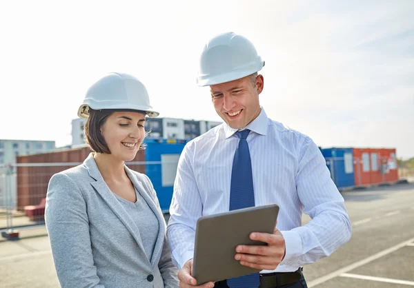 Constructeurs heureux en hardhats avec tablette PC à l'extérieur Image En Vente