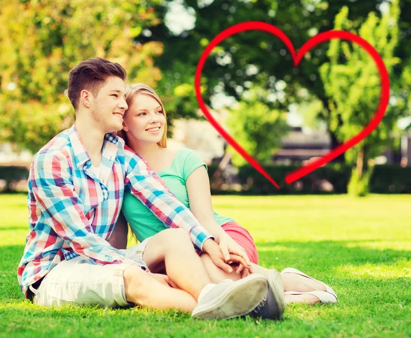 Smiling couple sitting on grass in summer park — Stock Photo, Image
