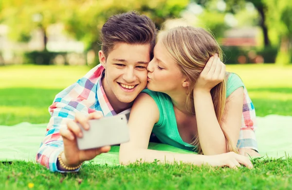 Uśmiechnięta para co selfie i pocałunki w parku — Zdjęcie stockowe