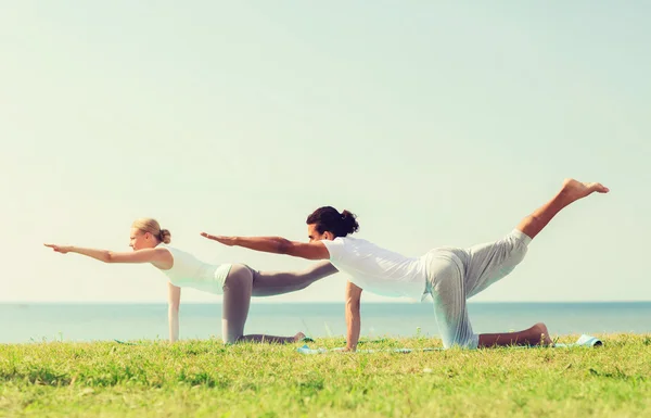 Coppia sorridente fare esercizi di yoga all'aperto — Foto Stock