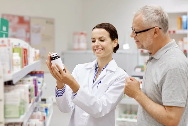 Farmacéutico mostrando droga al hombre mayor en la farmacia —  Fotos de Stock