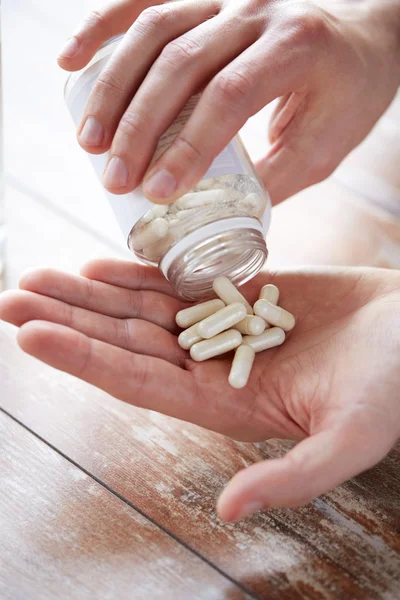 Close up of man pouring pills from jar to hand — Stock Photo, Image