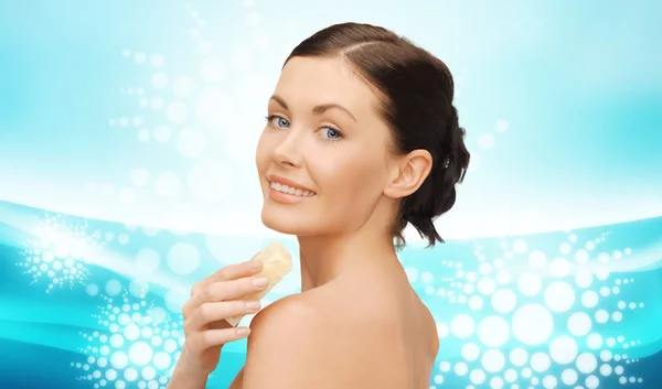 Woman with soap bar over blue wavy background — 图库照片