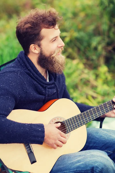 Sonriente hombre tocando la guitarra en camping —  Fotos de Stock