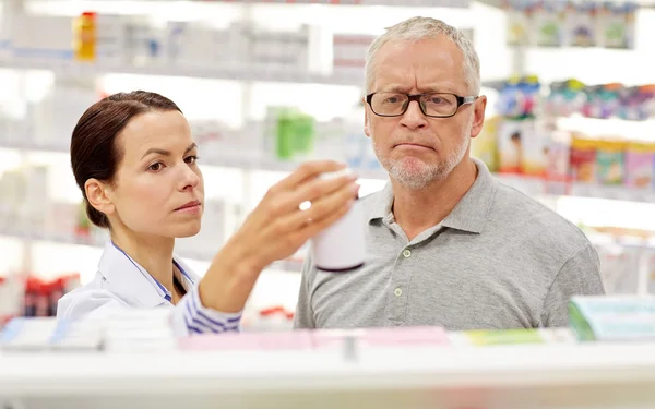 Apotekare visar läkemedel till äldre man på apotek — Stockfoto