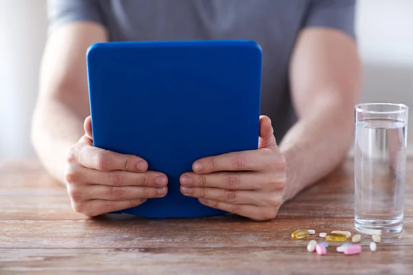 Primer plano de las manos con la tableta de la PC, pastillas y agua — Foto de Stock