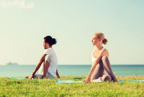 Glimlachend paar oefeningen maken yoga buiten — Stockfoto