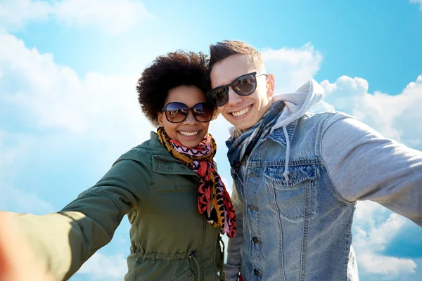 Счастливая пара подростков делает селфи над голубым небом — стоковое фото