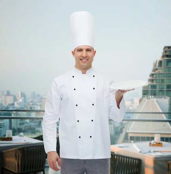 Cocinero macho feliz mostrando plato vacío —  Fotos de Stock