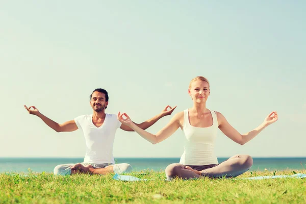 Coppia sorridente fare esercizi di yoga all'aperto — Foto Stock