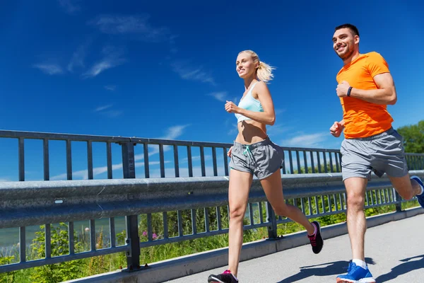 Sonriente pareja corriendo en verano junto al mar — Foto de Stock