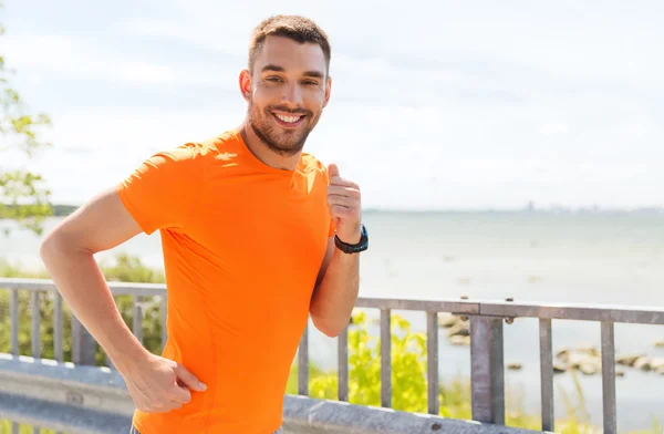 Smiling young man running at summer seaside — Stock Photo, Image