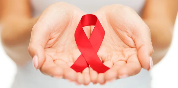 Hands holding red AIDS awareness ribbon — Stock Photo, Image