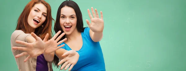 Happy student girls showing their palms over green — Stockfoto