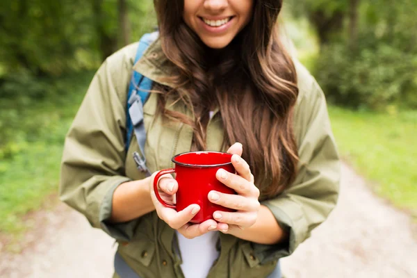 Lächelnde junge Frau mit Pokal und Rucksack beim Wandern — Stockfoto