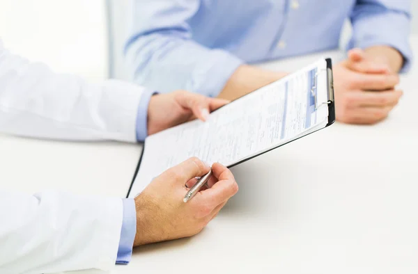 Close up of male doctor and patient with clipboard — Stock Photo, Image