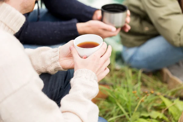 Detailní záběr turisty pití čaje z pohárů v táboře — Stock fotografie