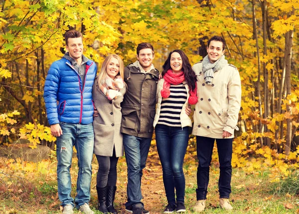 Group of smiling men and women in autumn park — Stock Photo, Image