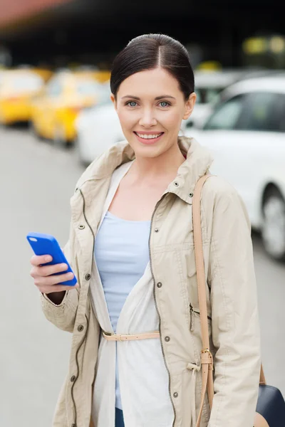 Smiling woman with smartphone over taxi in city — Stock Photo, Image