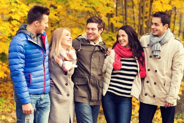 Group of smiling men and women in autumn park — Stock Photo, Image