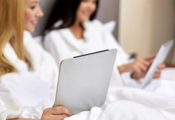 Gelukkig vrouwen in badjassen met tablet pc bij hotel — Stockfoto