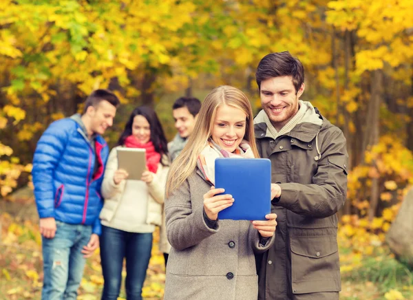 Gruppe lächelnder Freunde mit Tabletten im Park — Stockfoto