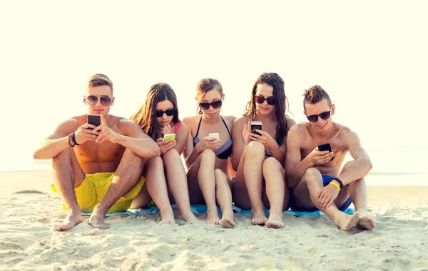 Amigos com smartphones na praia — Fotografia de Stock