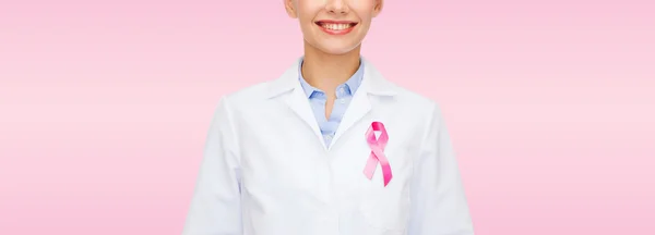 Smiling female doctor with cancer awareness ribbon — Stock Photo, Image