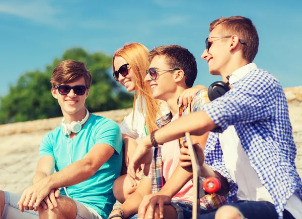 Gruppo di amici sorridenti seduti sulla strada della città — Foto Stock