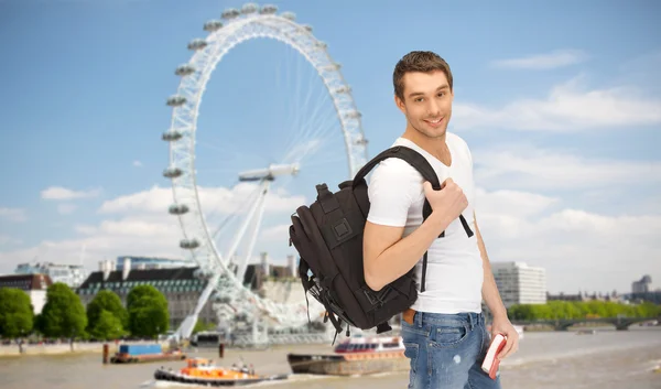 Felice giovane uomo con zaino e prenotare in viaggio — Foto Stock