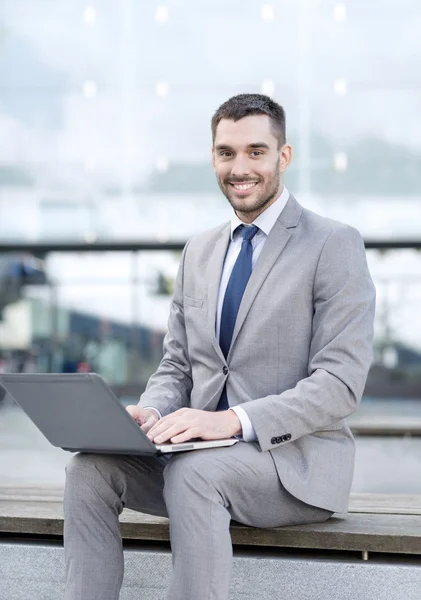 Sonriente hombre de negocios trabajando con el ordenador portátil al aire libre —  Fotos de Stock